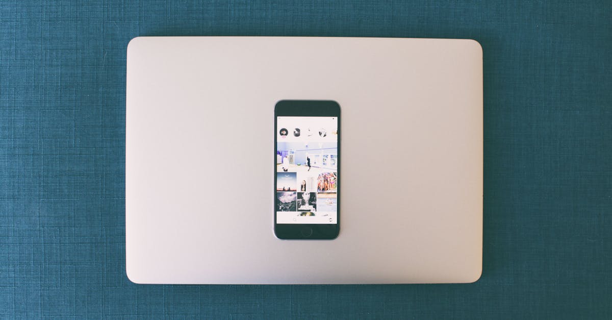 Flat lay of a smartphone on a laptop with social media photos on screen.
